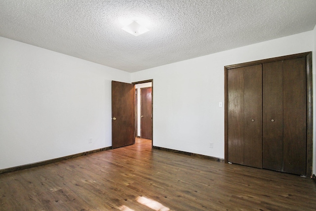 unfurnished bedroom featuring a textured ceiling, a closet, and dark wood-type flooring