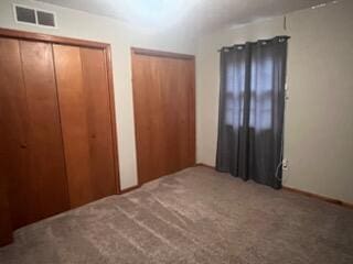 unfurnished bedroom featuring carpet floors and two closets