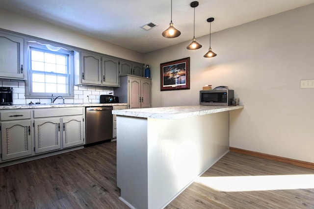 kitchen with kitchen peninsula, appliances with stainless steel finishes, dark hardwood / wood-style flooring, tasteful backsplash, and hanging light fixtures