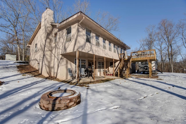 snow covered rear of property featuring a fire pit and a deck