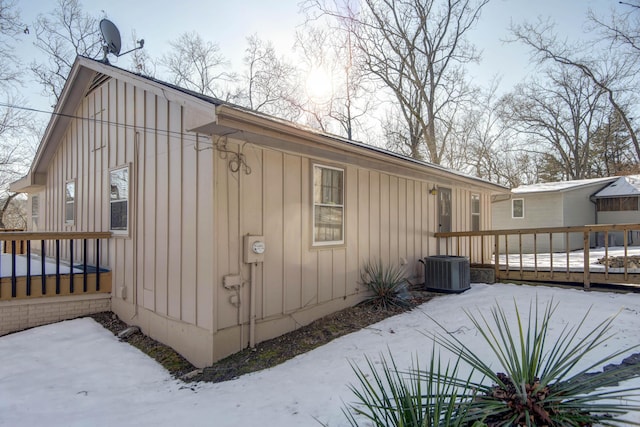 snow covered property with central AC and a deck