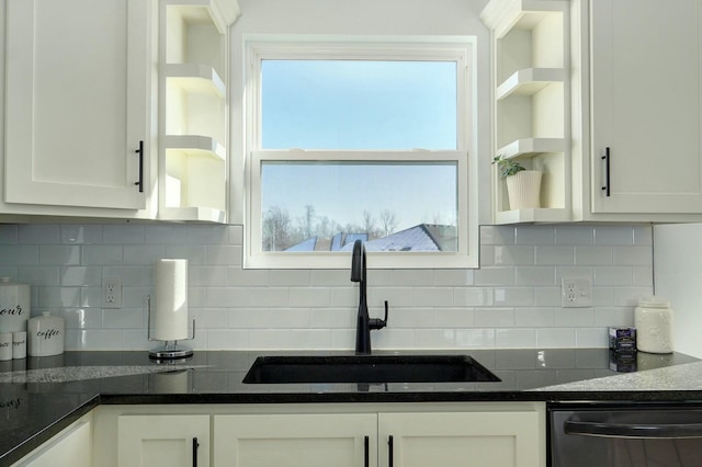 kitchen with white cabinetry, sink, black dishwasher, tasteful backsplash, and dark stone countertops