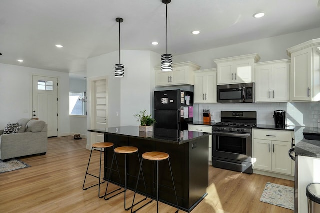 kitchen with backsplash, light hardwood / wood-style floors, decorative light fixtures, a kitchen island, and stainless steel appliances