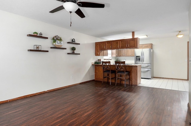 kitchen with kitchen peninsula, a breakfast bar, ceiling fan, light hardwood / wood-style flooring, and stainless steel fridge with ice dispenser