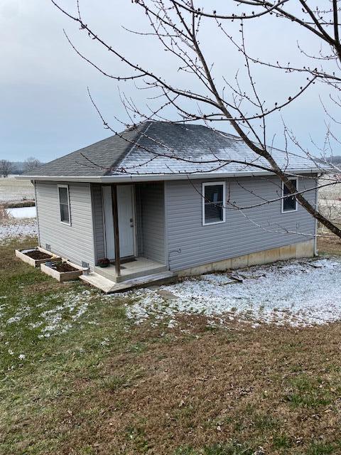 snow covered rear of property featuring a lawn