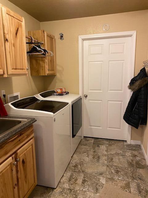 laundry room featuring washer and clothes dryer and cabinets