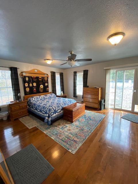 bedroom with a textured ceiling, hardwood / wood-style flooring, and ceiling fan