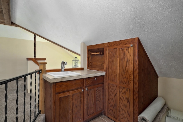 bathroom featuring a textured ceiling, vanity, and vaulted ceiling