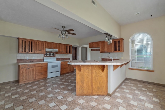 kitchen with white range with electric cooktop, a kitchen breakfast bar, decorative backsplash, and kitchen peninsula