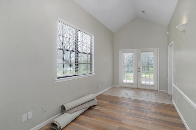 doorway featuring light hardwood / wood-style floors, vaulted ceiling, a wealth of natural light, and french doors