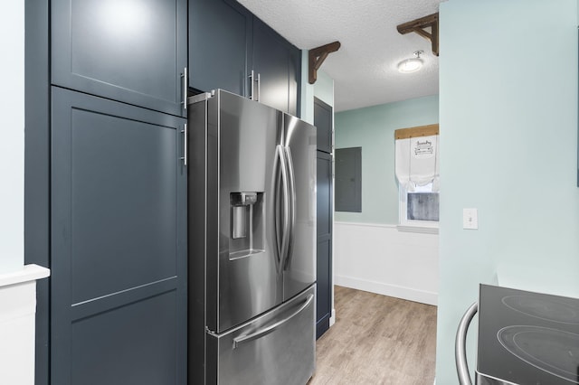 kitchen featuring a textured ceiling, stainless steel appliances, light hardwood / wood-style flooring, and electric panel