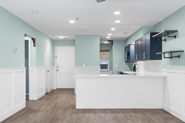 kitchen featuring appliances with stainless steel finishes, sink, light hardwood / wood-style flooring, and kitchen peninsula