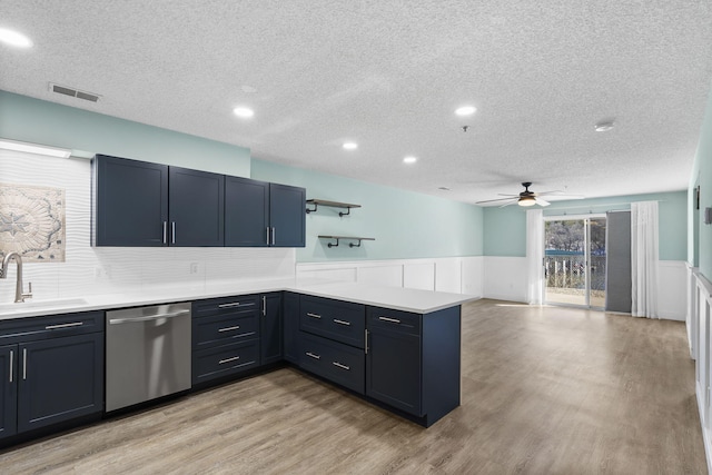 kitchen with kitchen peninsula, light wood-type flooring, stainless steel dishwasher, ceiling fan, and sink