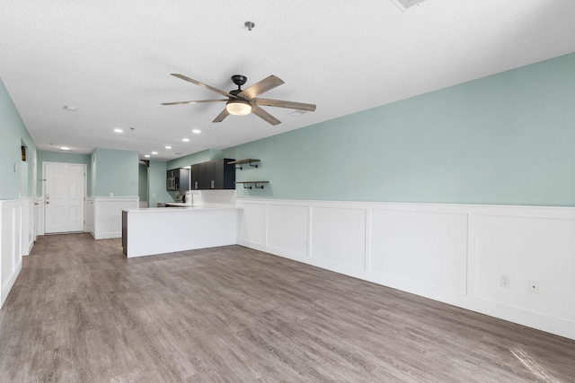 unfurnished living room with ceiling fan, wood-type flooring, and a textured ceiling