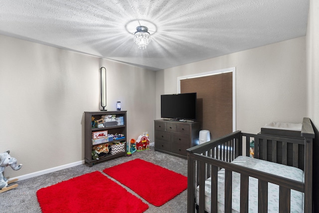 bedroom with carpet floors, a crib, and a textured ceiling