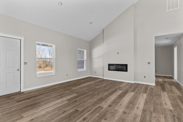 unfurnished living room with high vaulted ceiling and wood-type flooring