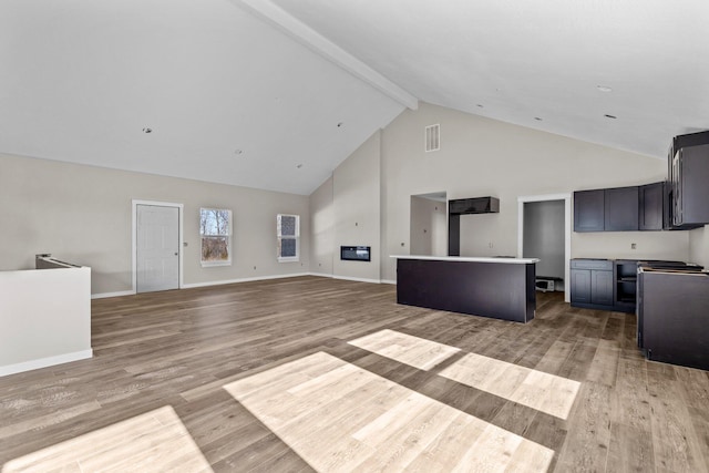 unfurnished living room featuring high vaulted ceiling, beam ceiling, and light wood-type flooring