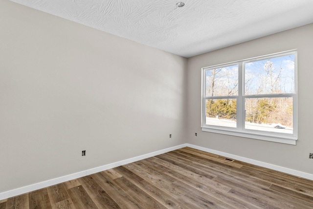 spare room with a textured ceiling and hardwood / wood-style flooring