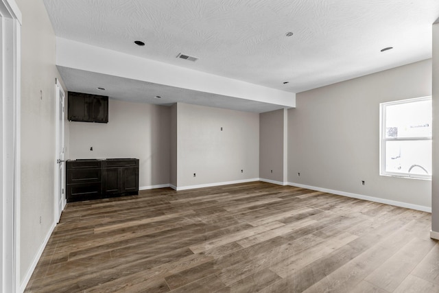 unfurnished room with a textured ceiling and hardwood / wood-style floors