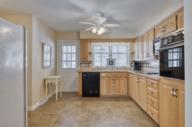 kitchen with backsplash, light brown cabinetry, black appliances, and sink