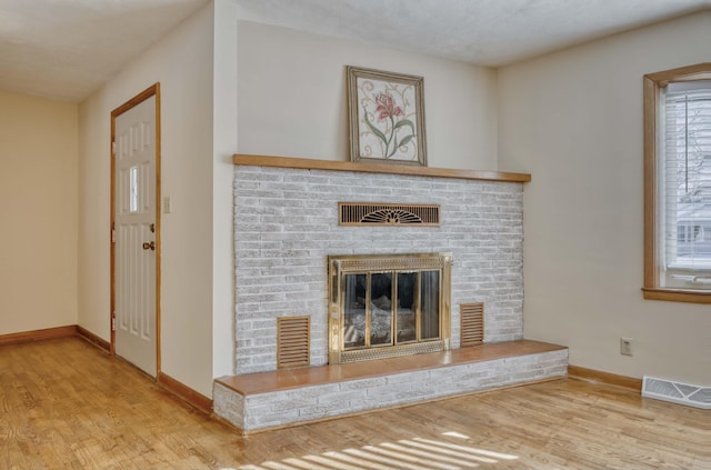 unfurnished living room featuring a brick fireplace and light hardwood / wood-style floors