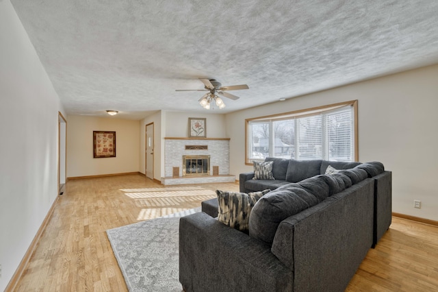 living room featuring ceiling fan, light wood-type flooring, and a fireplace