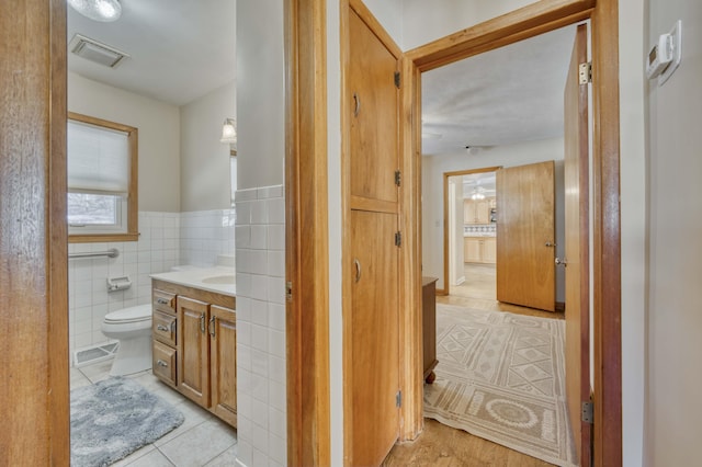 bathroom with tile walls, tile patterned flooring, vanity, and toilet