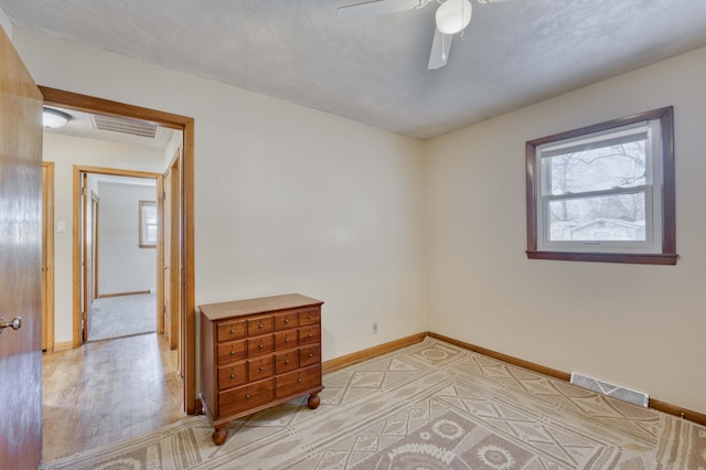 spare room featuring ceiling fan, light wood-type flooring, and plenty of natural light