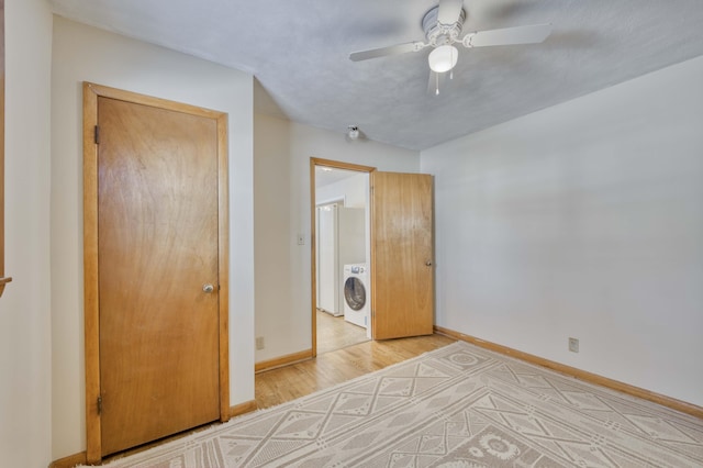 unfurnished bedroom featuring ceiling fan, light wood-type flooring, washer / dryer, and a closet