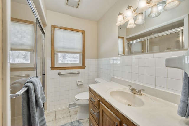 bathroom featuring tile walls, toilet, tile patterned floors, a shower with door, and vanity