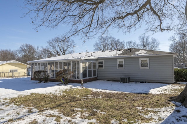 snow covered property featuring central air condition unit and a sunroom