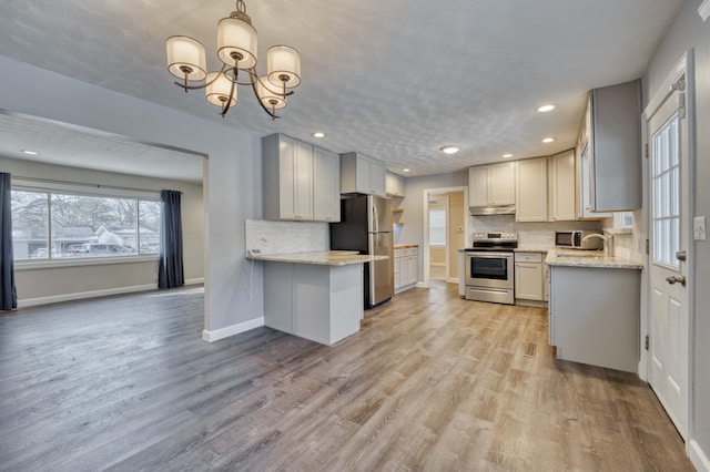 kitchen featuring light hardwood / wood-style floors, tasteful backsplash, light stone counters, and appliances with stainless steel finishes