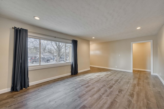 empty room with a textured ceiling and light hardwood / wood-style flooring