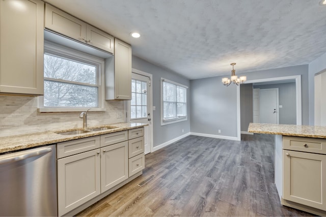 kitchen with sink, dishwasher, light stone counters, wood-type flooring, and backsplash