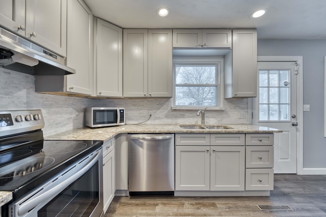 kitchen with appliances with stainless steel finishes, light stone counters, and sink