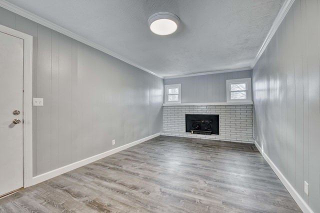 unfurnished living room featuring wood-type flooring, a brick fireplace, a textured ceiling, and crown molding