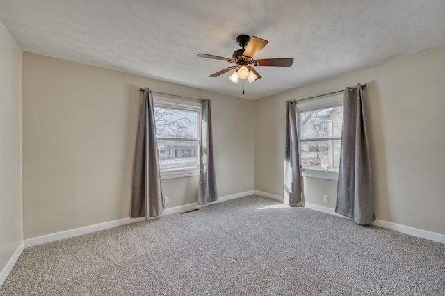 carpeted spare room featuring ceiling fan and a textured ceiling