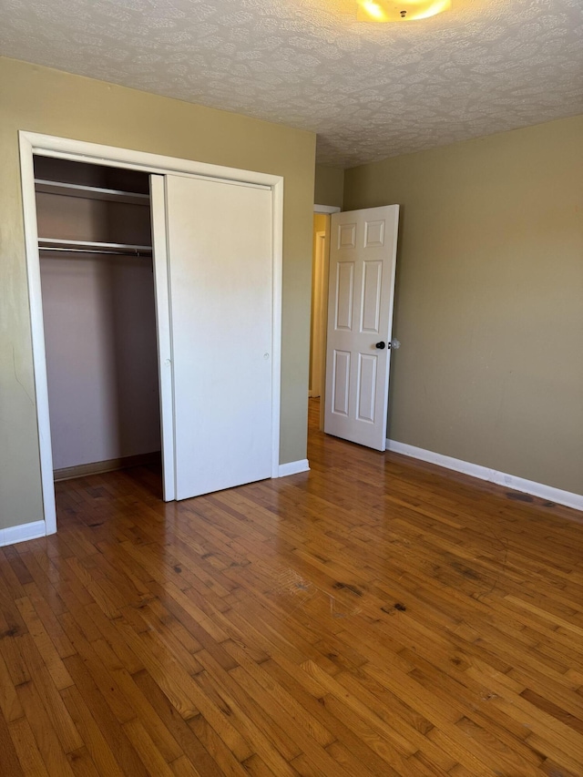 unfurnished bedroom featuring a textured ceiling, hardwood / wood-style floors, and a closet