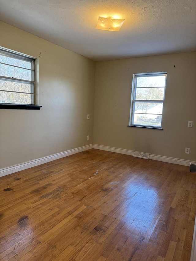 empty room with a textured ceiling and wood-type flooring