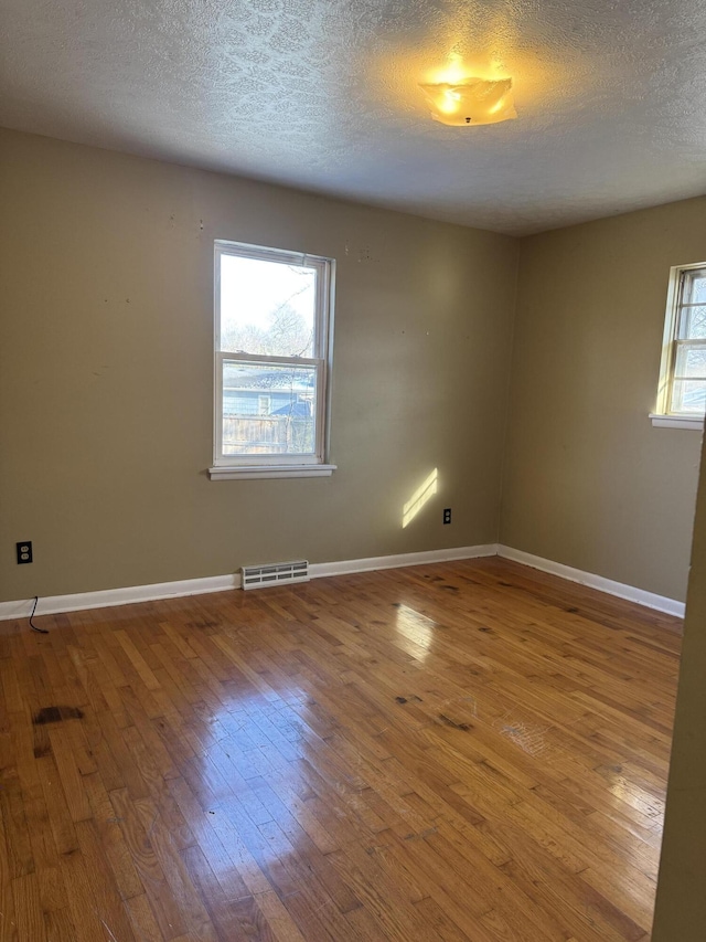 unfurnished room featuring hardwood / wood-style flooring and a textured ceiling