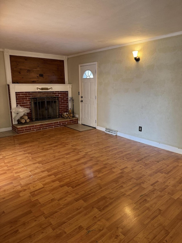 unfurnished living room featuring a brick fireplace, crown molding, and hardwood / wood-style floors