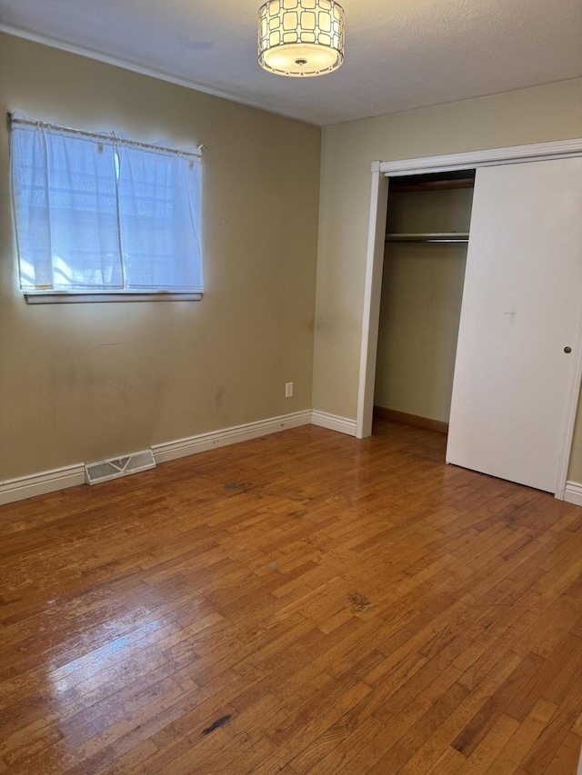 unfurnished bedroom with a closet and hardwood / wood-style flooring