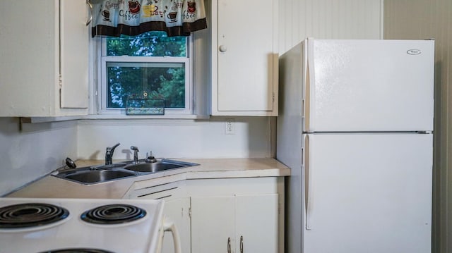 kitchen featuring sink, white appliances, and white cabinetry