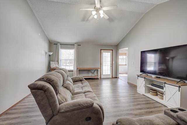 living room with lofted ceiling, a textured ceiling, light wood-type flooring, and ceiling fan