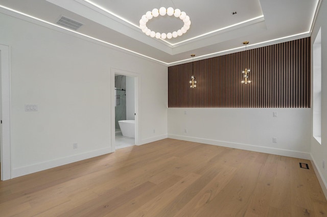 unfurnished room featuring light wood-type flooring and a raised ceiling