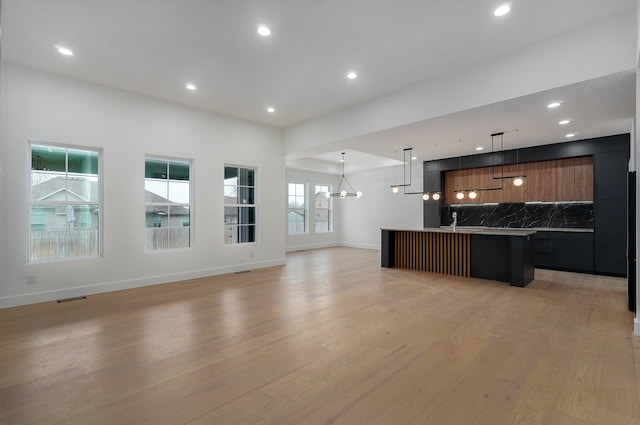 kitchen featuring a spacious island, a notable chandelier, pendant lighting, and decorative backsplash