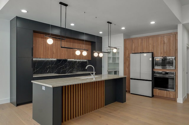 kitchen with decorative light fixtures, stainless steel appliances, a kitchen island with sink, and tasteful backsplash