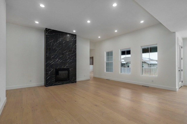 unfurnished living room featuring a high end fireplace and light hardwood / wood-style flooring