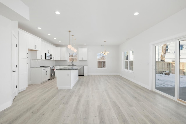 kitchen with stainless steel appliances, light wood-type flooring, a center island, pendant lighting, and white cabinets