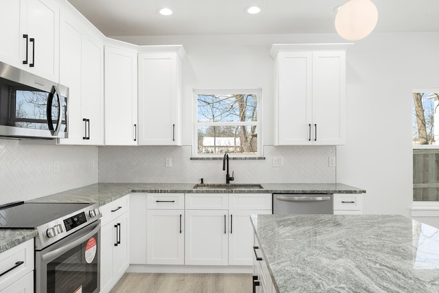 kitchen featuring appliances with stainless steel finishes, white cabinetry, and sink